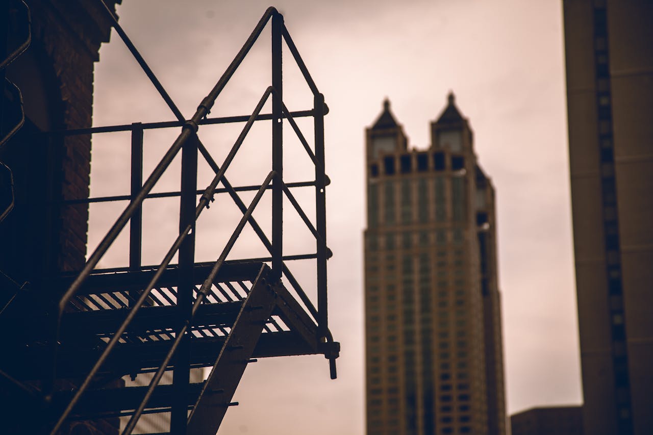 Dramatic urban scene featuring a fire escape silhouetted against the city skyline.