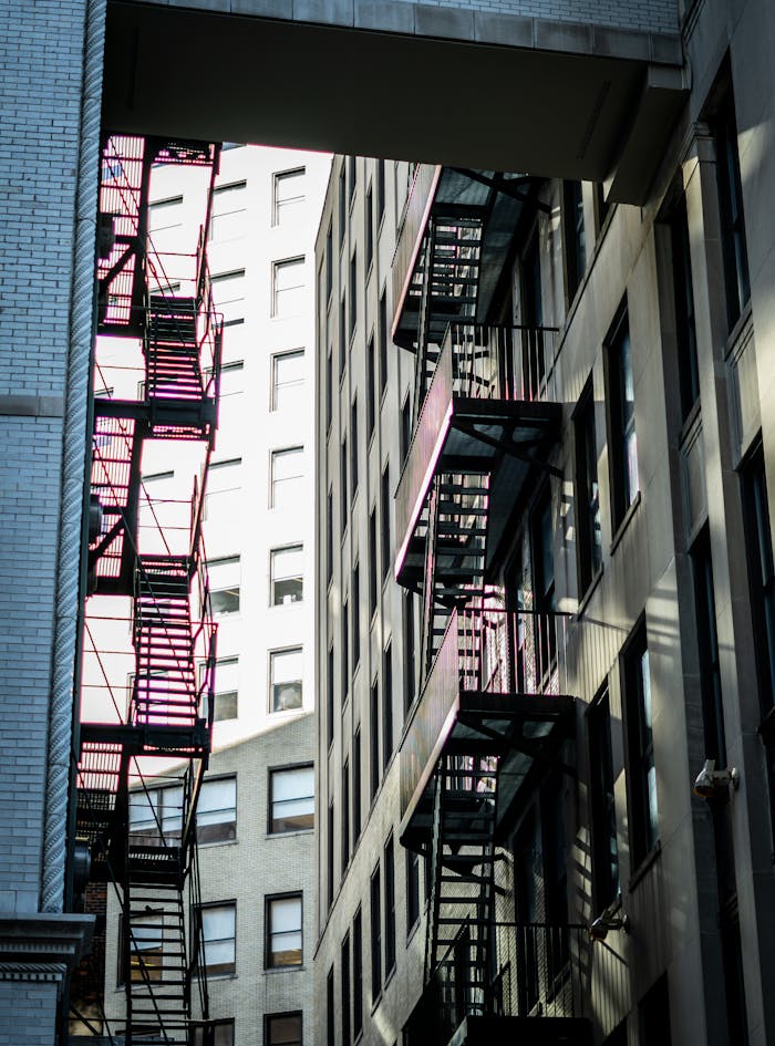 Sunlit urban buildings featuring fire escapes creating a striking architectural pattern.