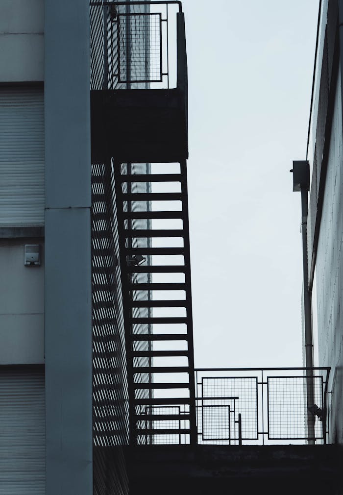Vertical low angle shot of a metal fire escape staircase with railings.